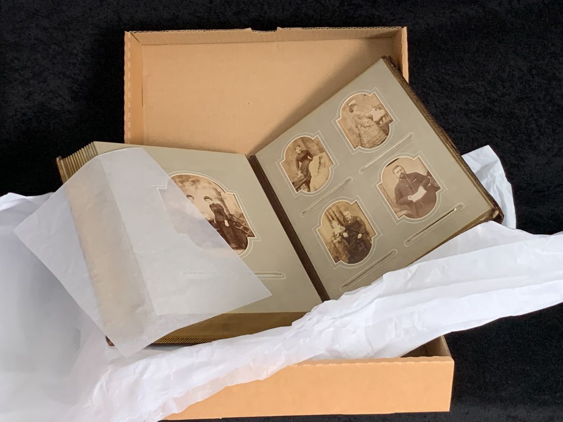 An old photo album about to be wrapped in acid-free tissue paper and placed into an acid-free clamshell box